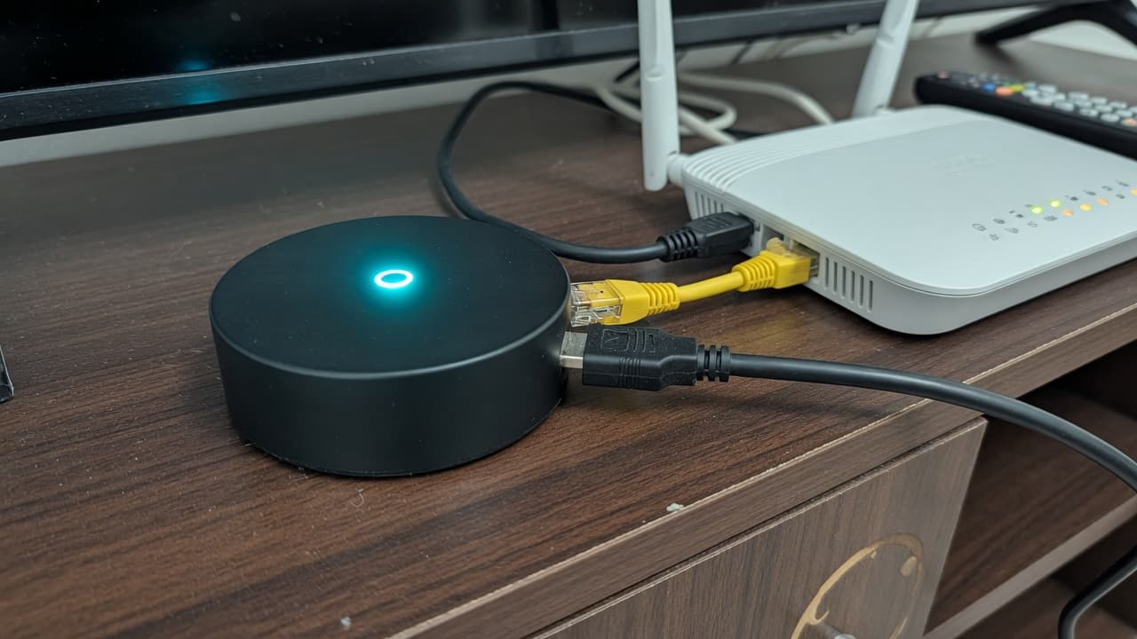 An unbranded streaming puck with a cyan light, connected by Ethernet to a home router, original BroadbandPicker photograph. Not an official Sky Stream product shot.